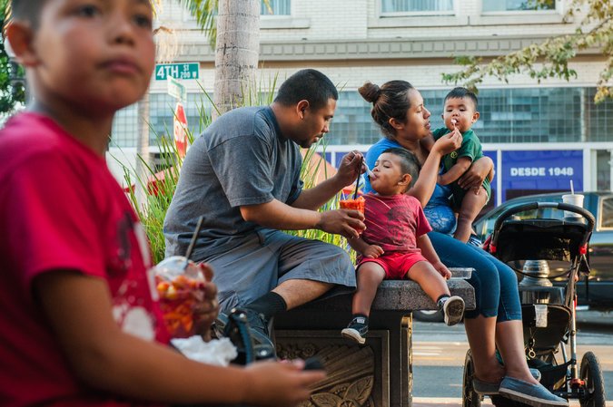 Mario and Janela Garibay with their children Jose and Rigo after buying fruit from a street vendor. Santa Ana’s historic downtown is clustered around what the official city map labels “Fourth Street,” but everyone here knows as “Calle Cuatro.” Credit, Andrew Cullen for The New York Times 